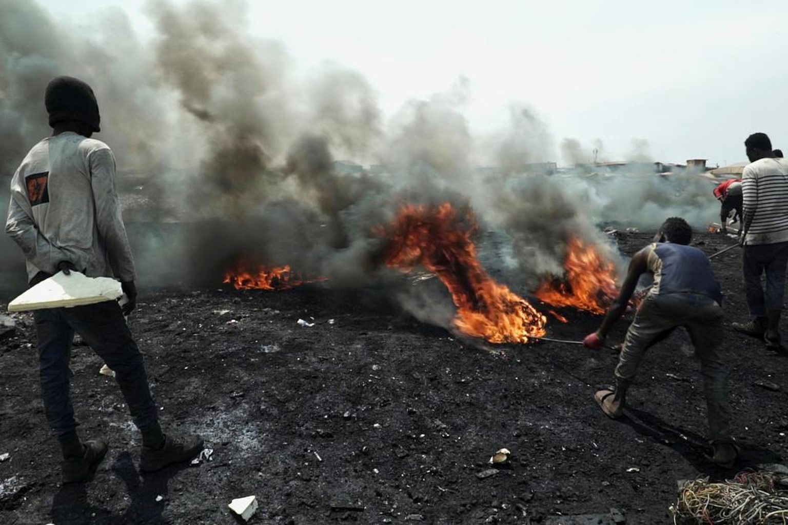 Junge Männer verbrennen in Accra, der Hauptstadt von Ghana, Elektrogeräte, um an verwertbares Metall zu kommen.