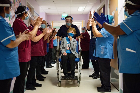 epa08869682 Margaret Keenan, 90, is applauded by staff as she returns to her ward after becoming the first person in the United Kingdom to receive the Pfizer/BioNtech covid-19 vaccine at the start of  ...