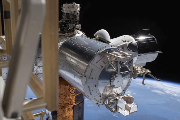 This July 1, 2020 photo made available by NASA shows the SpaceX Crew Dragon, right, docked to the International Space station, during a spacewalk conducted by astronauts Bob Behnken and Chris Cassidy. ...