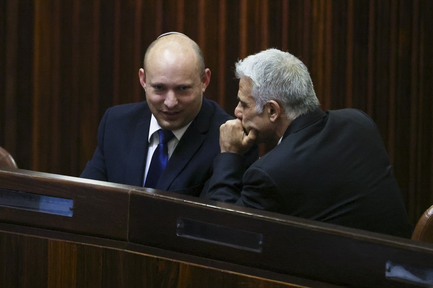 Yamina party leader Naftali Bennett, left, smiles as he speaks to Yesh Atid party leader Yair Lapid during a special session of the Knesset, whereby Israeli lawmakers elect a new president, at the ple ...