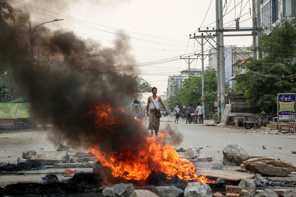 epa09087749 A demonstrator looks on along burning debris during a protest against the military coup in Mandalay, Myanmar, 21 March 2021. Anti-coup protests continued despite the intensifying violent c ...