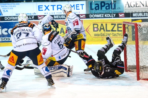 Le joueur zougois Timo Helbling, gauche, lutte pour le puck avec le joueur fribourgeois Killian Mottet, droite, lors de la rencontre du championnat suisse de hockey sur glace de National League, LNA,  ...