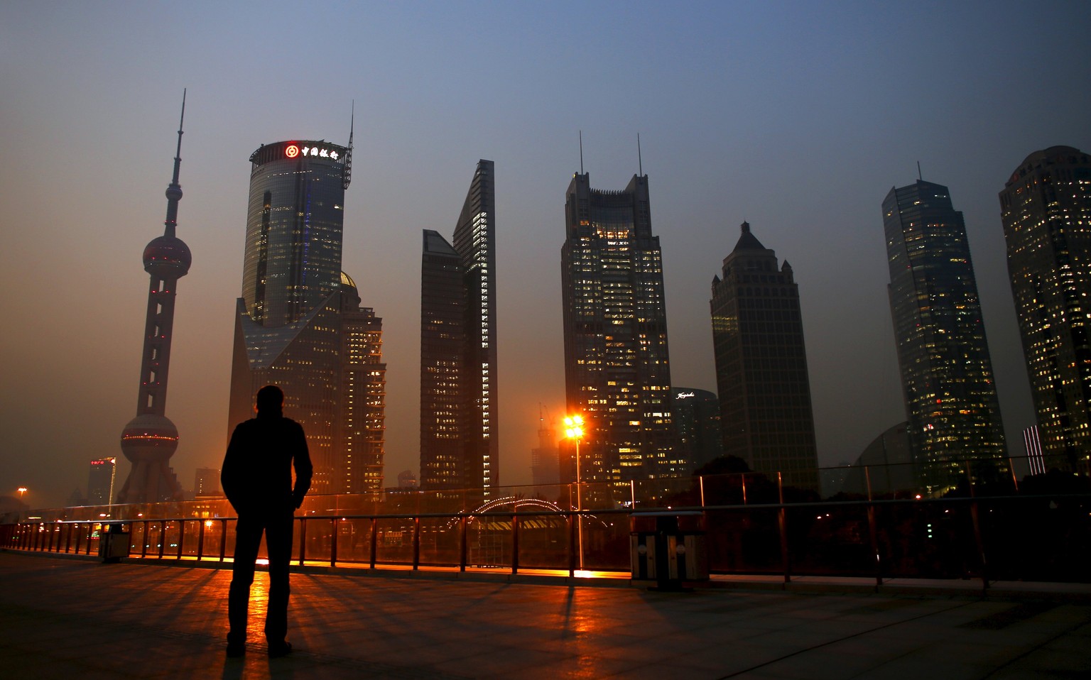 A man looks at the Pudong financial district of Shanghai in this November 20, 2013 file photo. Sentiment at some of Asia&#039;s biggest firms deteriorated again in the fourth quarter, falling to a fou ...
