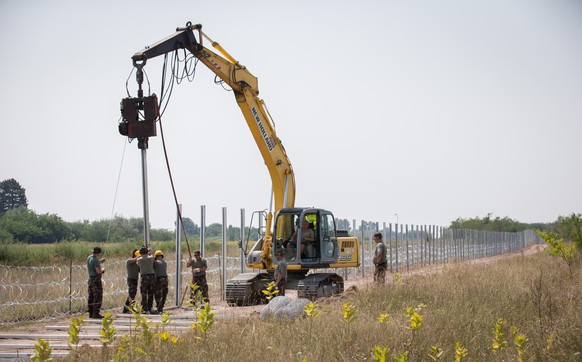 SZEGED, HUNGARY - AUGUST 12: Servicemen from the Hungarian Army construct a new fence along the border of Serbia with Hungary near the village of Asotthalom on August 12, 2015 near Szeged, Hungary. Hu ...