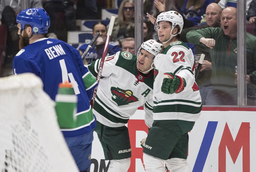 Minnesota Wild&#039;s Kevin Fiala, right, of Switzerland, and Zach Parise celebrate Fiala&#039;s goal as Vancouver Canucks&#039; Jordie Benn skates past during the first period of an NHL hockey game W ...