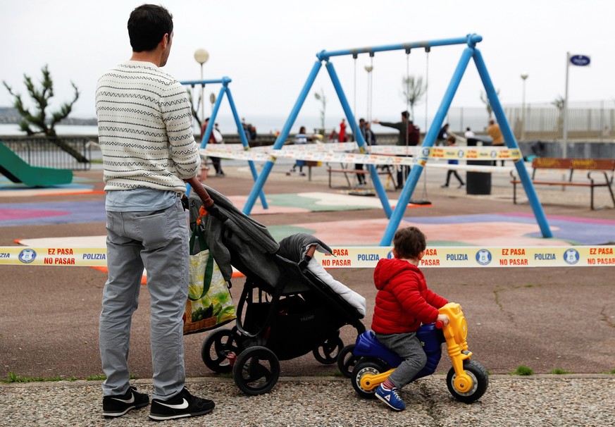 epa08385082 A man and his son look at a children&#039;s playground closed to the public as they go for a walk amid the ongoing coronavirus COVID-19 pandemic in San Sebastian, Spain, 26 April 2020, on  ...