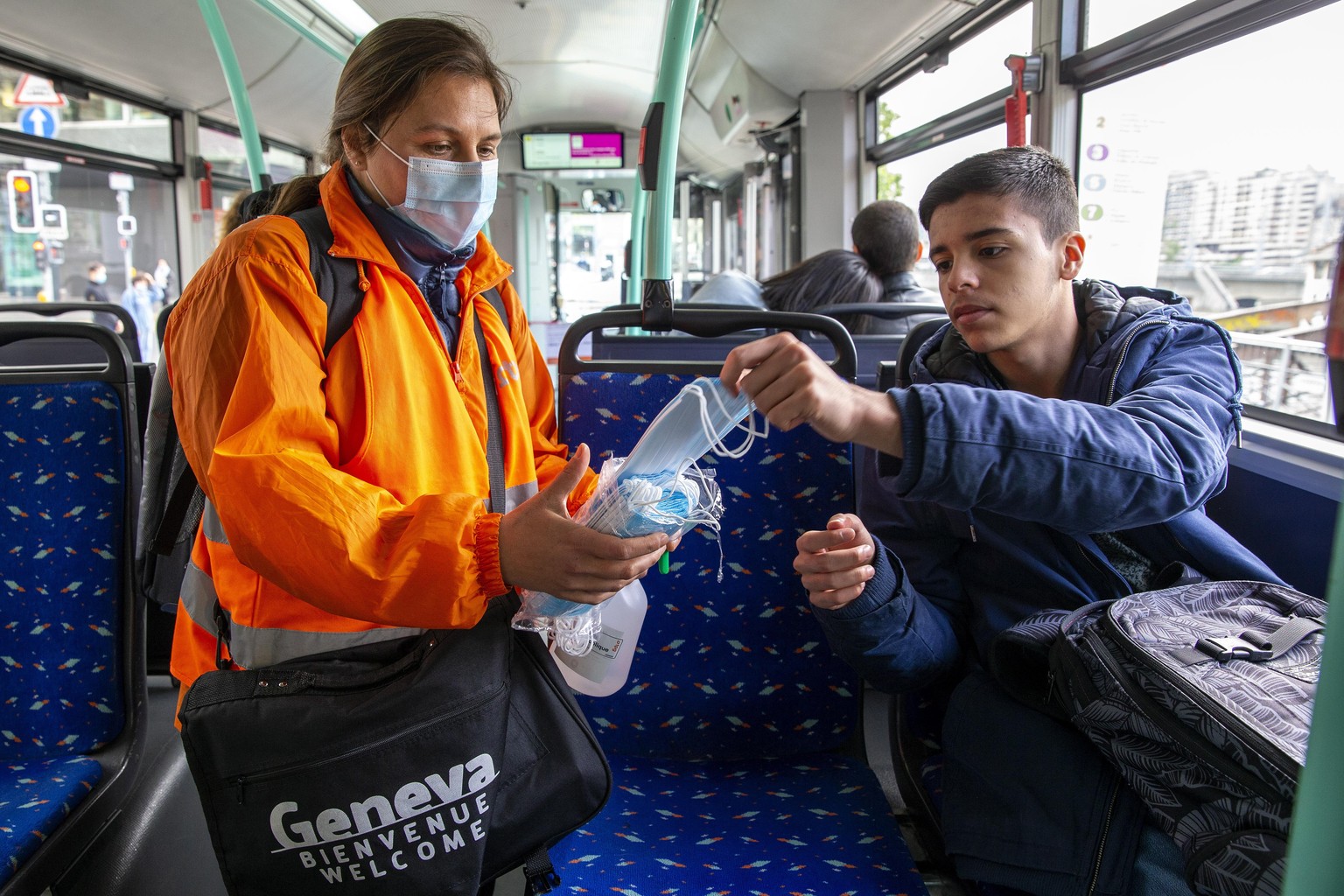 epa08417813 A member staff of the Transports publics genevois, TPG, (Geneva Public Transport), distributes protective face masks as a preventive mesure against the spread the coronavirus COVID-19 to p ...