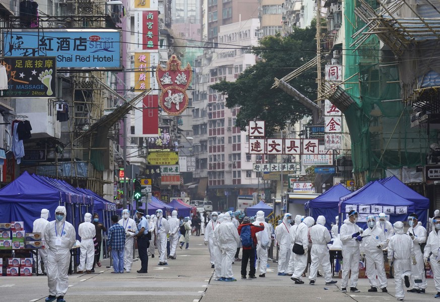 Government investigators wearing protective suits, gather in the Yau Ma Tei area, in Hong Kong, Saturday, Jan. 23, 2021. Thousands of Hong Kong residents will be locked down in an unprecedented move b ...