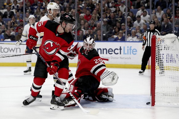 New Jersey Devils defenseman Mirco Mueller (25) and goaltender Mackenzie Blackwood (29) watch the puck enter the net during the second period of an NHL hockey game against the Buffalo Sabres, Saturday ...