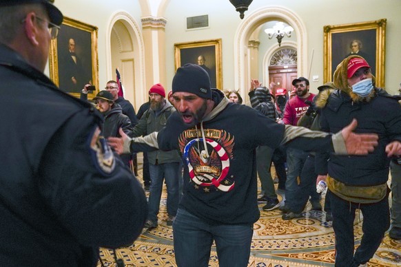 FILE - In this Jan. 6, 2021, file photo, Trump supporters gesture to U.S. Capitol Police in the hallway outside of the Senate chamber at the Capitol in Washington. Doug Jensen, an Iowa man at center,  ...