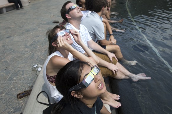 epa06155181 People at the National Gallery of Art Sculpture Garden look at the solar eclipse at the National Mall in Washington, DC, USA, 21 August 2017. The 21 August 2017 total solar eclipse will la ...