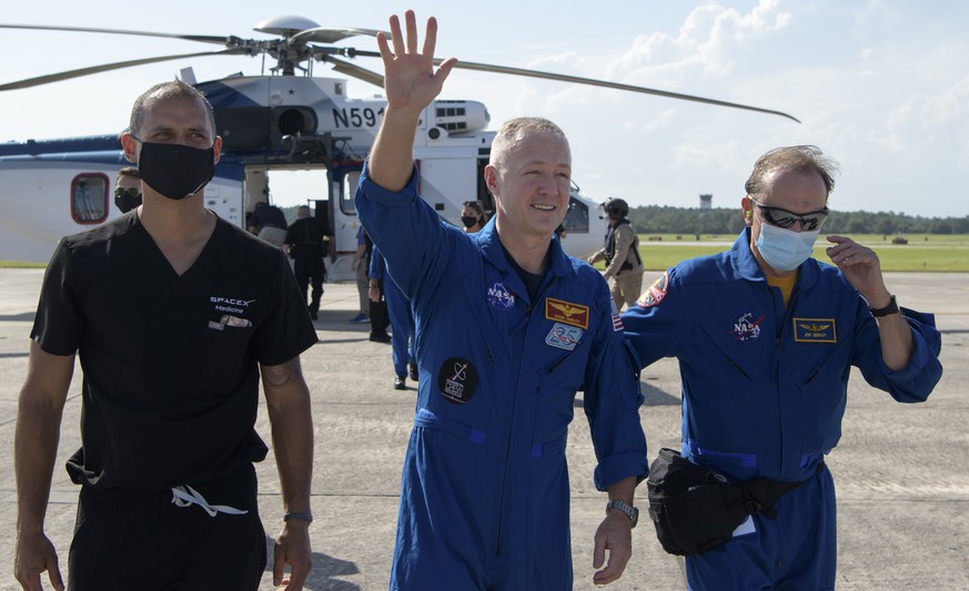 NASA astronaut Douglas Hurley waves to onlookers as he boards a plane at Naval Air Station Pensacola to return him and NASA astronaut Robert Behnken home to Houston a few hours after the duo landed in ...