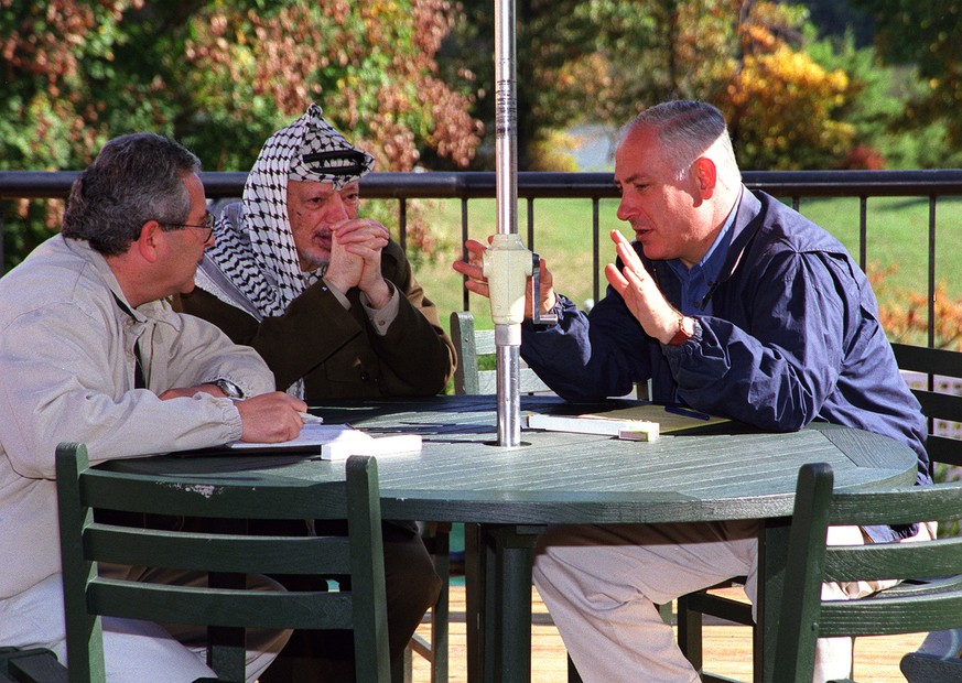 Israeli Prime Minister Benjamin Netanyahu, right, talks with Palestinian leader Yasser Arafat Monday, Oct. 19, 1998, at the Wye Convention Center in Wye Mills, Md. The man at left is an unidentified t ...