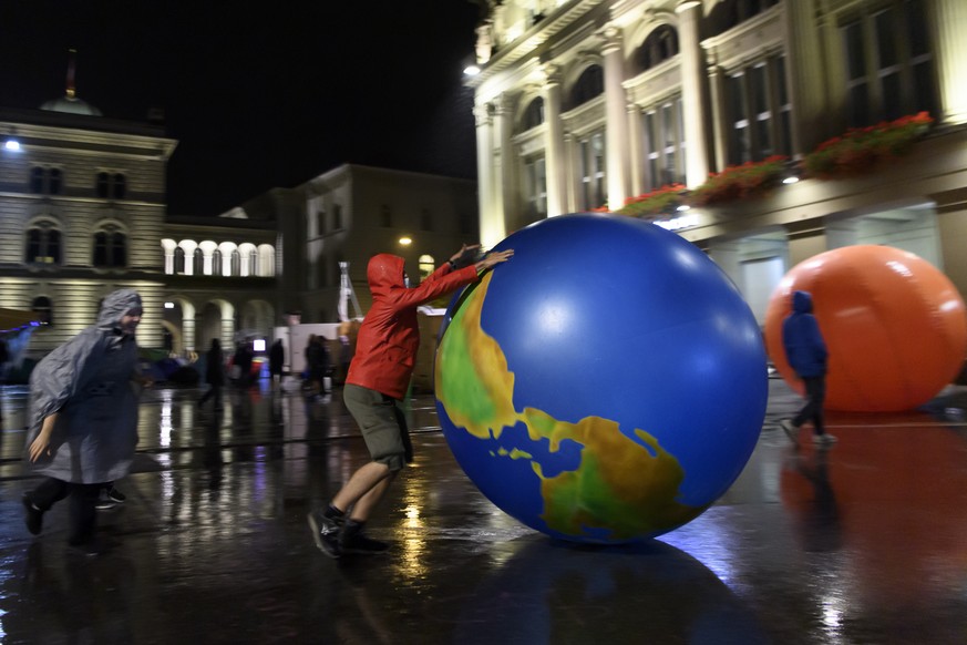 The climate activists play with an inflatable world globe under the rain, during their ?Rise up for Change? week of action in front of the Swiss parliament building, the ??Bundeshaus??, where the Swis ...