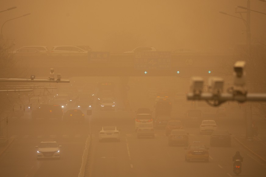 Cars are driven along a street amid a sandstorm during the morning rush hour in Beijing, Monday, March 15, 2021. The sandstorm brought a tinted haze to Beijing&#039;s skies and sent air quality indice ...