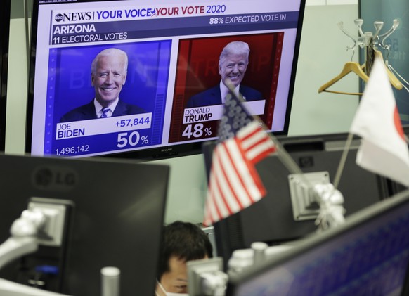 A trader works at a foreign exchange trading office as a monitor shows file images of U.S. President Donald Trump, right, and Democratic presidential candidate former Vice President Joe Biden for thei ...