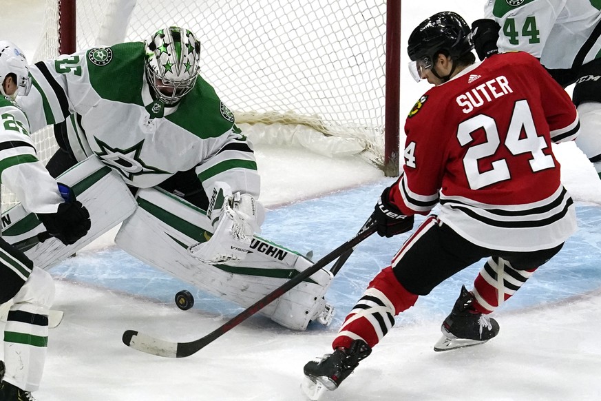 Dallas Stars goaltender Anton Khudobin, left, makes a save on a shot by Chicago Blackhawks center Pius Suter during the first period of an NHL hockey game in Chicago, Sunday, May 9, 2021. (AP Photo/Na ...
