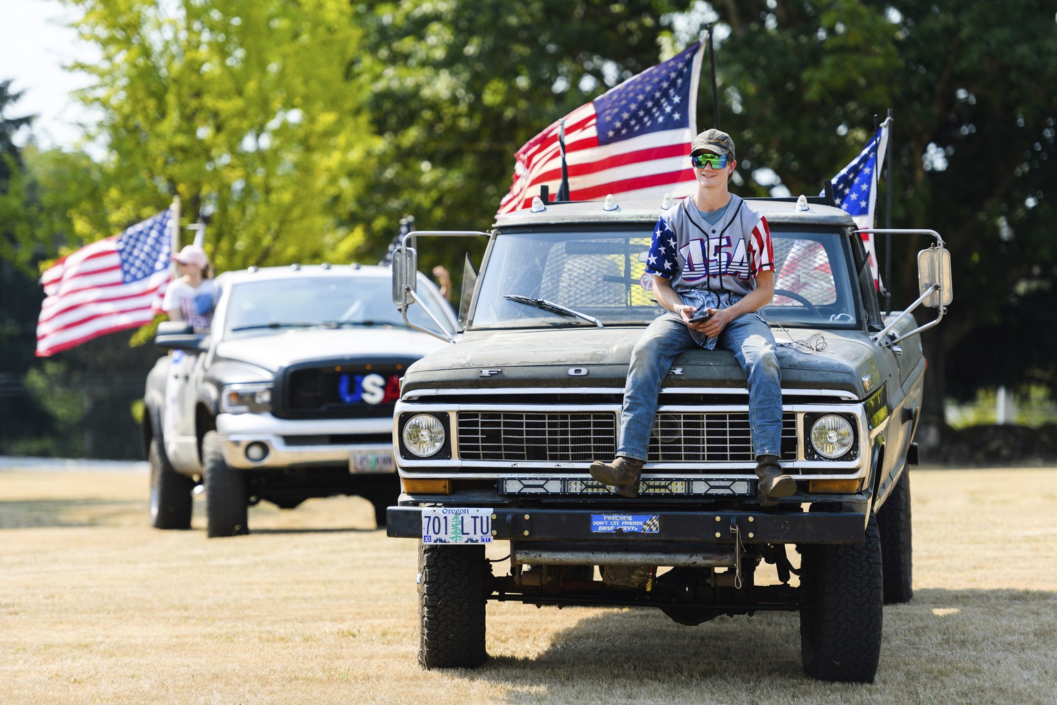 Riley Brumeister, 18, of Gresham, attends his first Trump rally atop the hood of his 1970 Ford F-250, at Clackamas Community College in Oregon City, Ore., Monday, Sept. 7, 2020. (AP Photo/Michael Arel ...