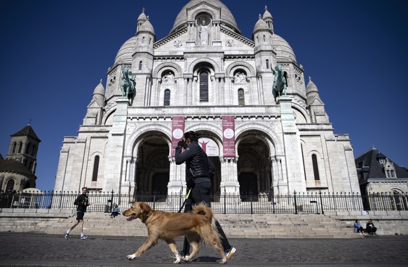 epa08315963 A man walks his dog in the deserted streets in Montmartre, in Paris, France, 23 March 2020. France is under lockdown in an attempt to stop the widespread of the SARS-CoV-2 coronavirus caus ...