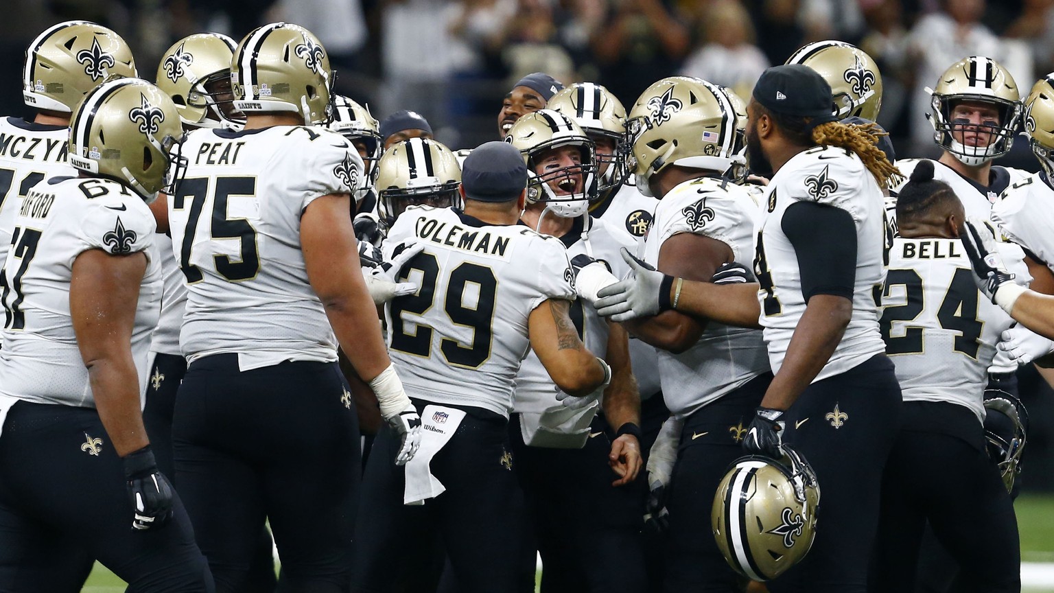 New Orleans Saints players surround quarterback Drew Brees after Brees broke the NFL all-time passing yards record in the first half of an NFL football game against the Washington Redskins in New Orle ...
