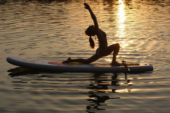 epa04836366 A photo made available 08 July 2015 of a member of the SOULnok SUP group performing yoga excercises on a Stand Up Paddle board on the backwater of the river Tisza of Alcs in Szolnok, some  ...