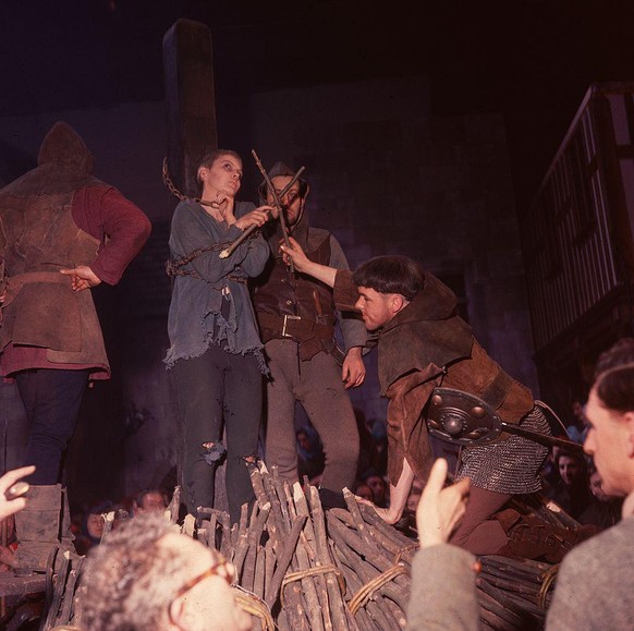 1957: Jean Seberg (1938 - 1979) as St Joan stands chained to the stake as a bonfire is built around her. In the foreground members of the film crew oversee the proceedings. Directed by Otto Preminger  ...